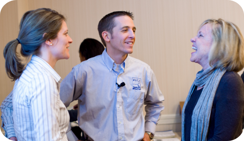 Three people engaged in conversation and smiling at each other.