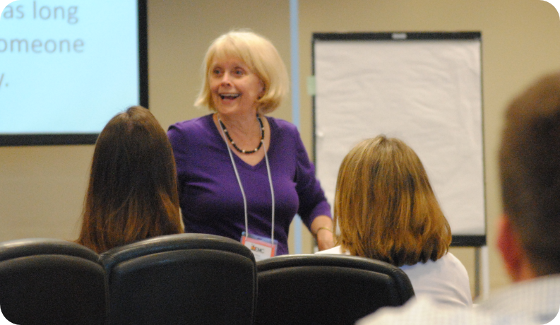Professional development facilitator leads an interactive training session for educators in a classroom setting, with attendees seated and engaged in the discussion.